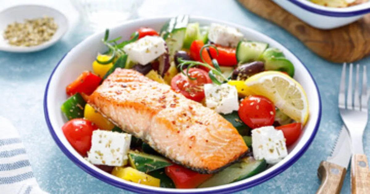 A plate of Mediterranean Salmon topped with olives, tomatoes, and a drizzle of olive oil.